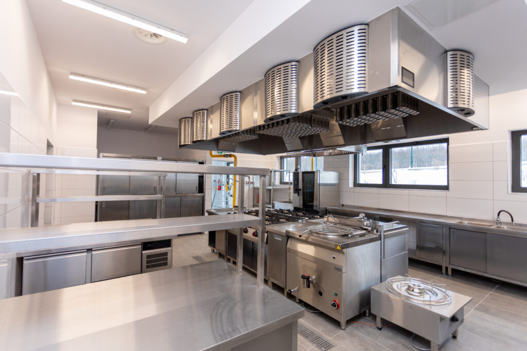 A contemporary commercial kitchen featuring stainless steel appliances and bright, efficient lighting.